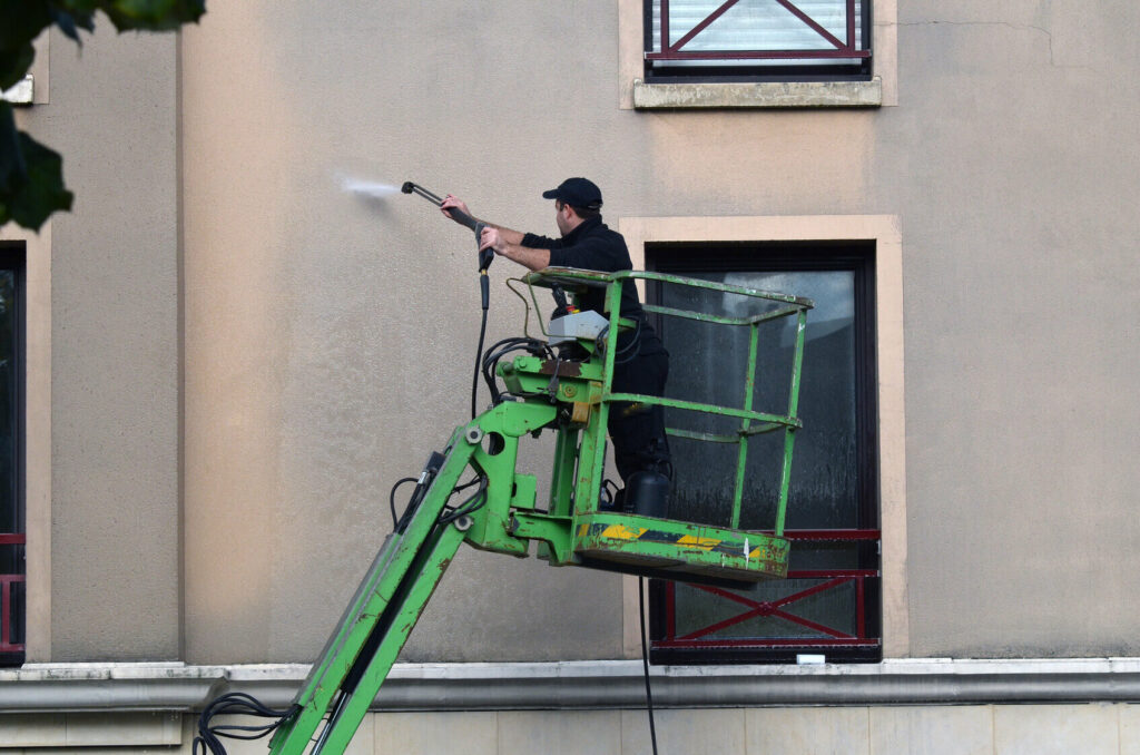 Technicien procédant à des travaux de ravalement de façade en rénovation à Lyon